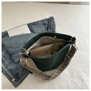 Detail of spacious dark green corduroy bucket bag interior with a wide patterned strap