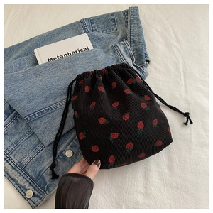 Détail du sac à cordon en velours côtelé noir avec motifs fraises sur denim