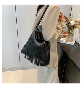 Close-up of black fringed tote bag with pebbled leather and gold ring hardware detail