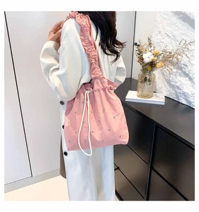 Detail of pink rhinestone bucket bag with ruffled shoulder strap and white drawstring closure