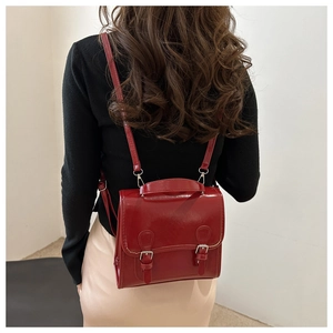 Detail of red glossy patent leather convertible backpack with vintage satchel design