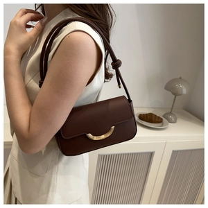 Détail d'un sac à bandoulière en cuir marron avec fermoir demi-lune doré et bandoulière