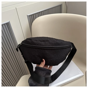 Detail shot of black chest bag with unique crinkled texture fabric and wide strap