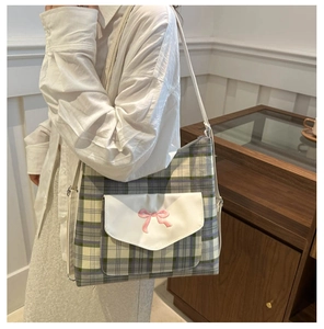 Detailed shot of a green and blue plaid tote bag with a pink bow and front pocket