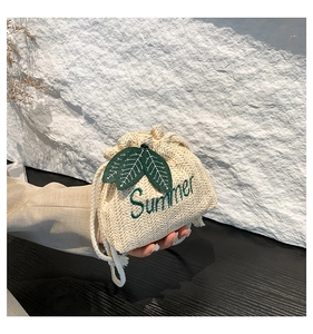 Detail of woven straw bucket bag with green leaf embroidery and Summer text detail