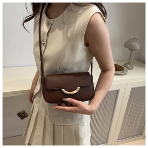 Brown matte leather crossbody square bag with gold crescent buckle on a model