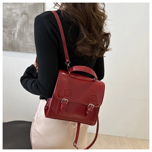 Close-up of a glossy red PU leather backpack with double buckle design and handle