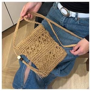 Detail of bohemian straw crossbody bag with intricate hollow patterns and wooden beads