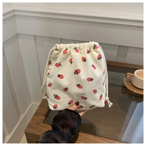 Gros plan d'une pochette en velours côtelé à motif fraise tenue à la main