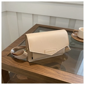 Chic beige crossbody bag with wide strap and fashion logo on a coffee table