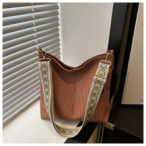 Détail du sac seau tissé marron roux avec une large bandoulière à motif géométrique