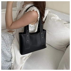 Detail of black faux leather tote with contrast white stitching and gold studs