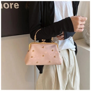 Dettaglio della borsa rosa perlata con borchie a cuore dorate e chiusura vintage