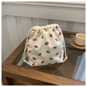 Détail du sac à cordon en velours côtelé avec motifs fraises sur table bois