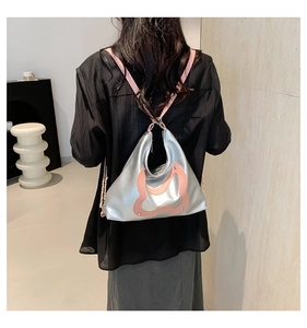 Detail der silbernen Metallic-Hobo-Tasche mit rosa Gurt und Kette an einem Modell