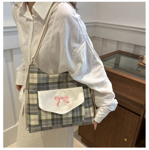 Detail of canvas tote bag featuring green checkered pattern and pink bow embroidery