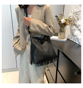 Detail of a black pebbled leather tassel shoulder bag with golden metal eyelets