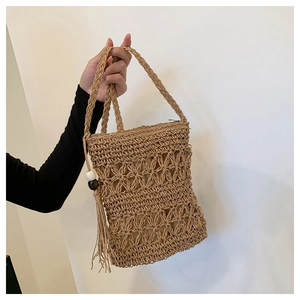Detail of bohemian straw bag featuring hollow floral pattern and beaded tassels