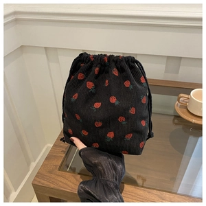 Détail de la broderie fraise sur sac à cordon en velours côtelé noir au fini texturé