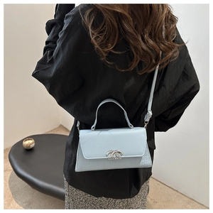 Detail of light blue crossbody bag with crocodile texture and silver metal lock