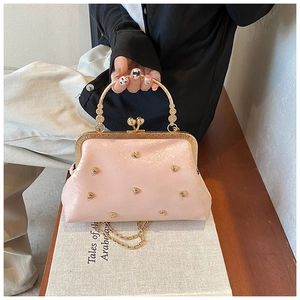Dettaglio borsa rosa glitterata con borchie dorate a cuore e tracolla a catena in metallo