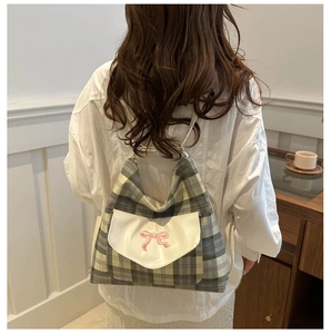 Detail of plaid backpack featuring pink bow embroidery and white leather flap detail