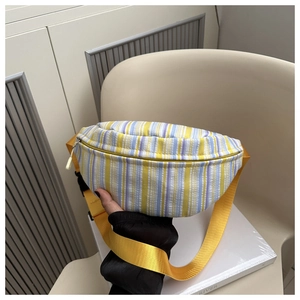 Détail du sac bandoulière rayé coloré avec sangle jaune dans un décor d'intérieur