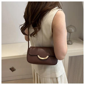Femme élégante portant un sac baguette en cuir marron mat dans une pièce moderne