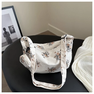 Détail d'un sac cabas en velours côtelé fleuri avec mini pochette assortie sur un tabouret