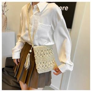 Close-up of bohemian straw crossbody bag with white beads and elegant long fringe detail