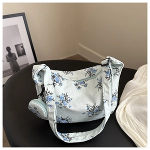Détail d'un sac à bandoulière en velours côtelé bleu clair à fleurs avec petite pochette
