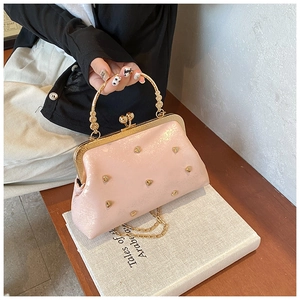 Dettaglio borsa rosa con borchie a cuore dorate e chiusura a scatto in metallo chic