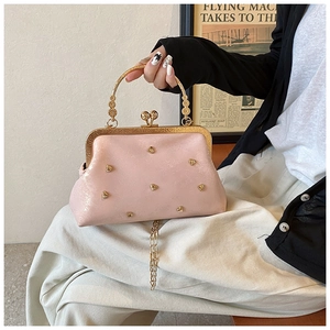 Dettaglio borsa vintage rosa con borchie a cuore e manico in metallo intagliato