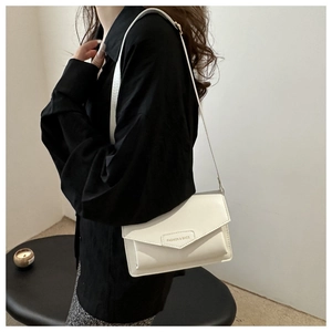 Close-up of a white minimalist shoulder bag with flap closure and fashion text branding