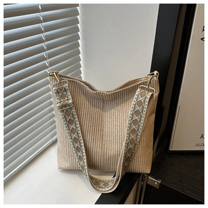 Détail d'un sac cabas tissé beige avec une large bandoulière à broderie géométrique et boucles