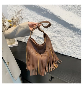 Close-up of vintage brown fringe tote bag with litchi grain leather and metal eyelets