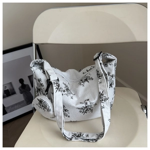 Gros plan du sac bandoulière en velours côtelé blanc à fleurs avec petite pochette amovible