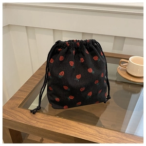 Vue détaillée du sac à cordon en velours côtelé noir avec broderie fraise sur table