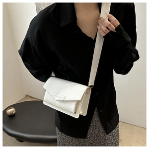Close-up of white crossbody bag with FASHION & BAGS logo and wide strap on black shirt