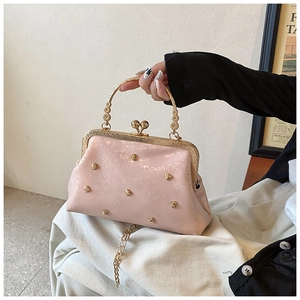 Dettaglio borsa rosa lucida con borchie a cuore dorate e manico in metallo inciso