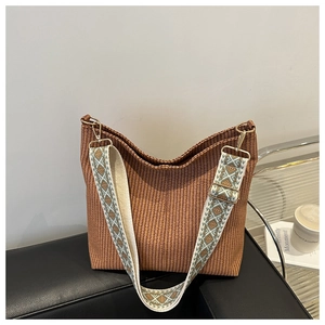 Detail of a brown woven hobo bag featuring a patterned ethnic-style wide shoulder strap