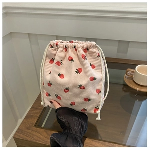 Détail de la texture d'un pochon en velours côtelé rose avec imprimé de fraises rouges