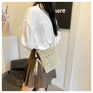 Detailed close-up of woven hollow pattern and tassel on bohemian straw crossbody bag