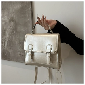 Detail of pearlescent beige handbag showing soft texture and silver buckle straps