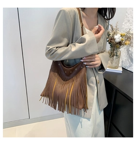 Close-up of brown fringe shoulder bag with bohemian tassels and metallic eyelets details