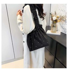 Detail of black drawstring tote bag with ruffle strap and sparkling rhinestone pattern
