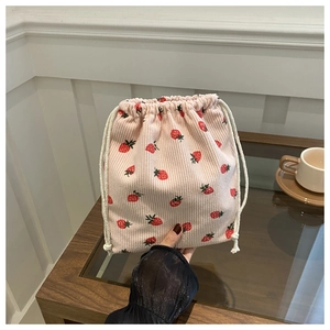 Gros plan d'un sac à cordon en velours rose avec imprimé fraises tenu à la main