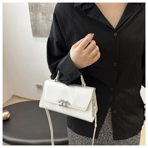 Detail of white crocodile embossed texture and silver metal buckle on a chic handbag