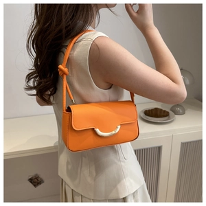Détail du sac baguette orange avec boucle dorée et bandoulière à nœud élégante