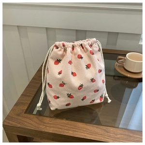 Détail de la pochette en velours côtelé rose avec imprimé fraise et texture douce au toucher